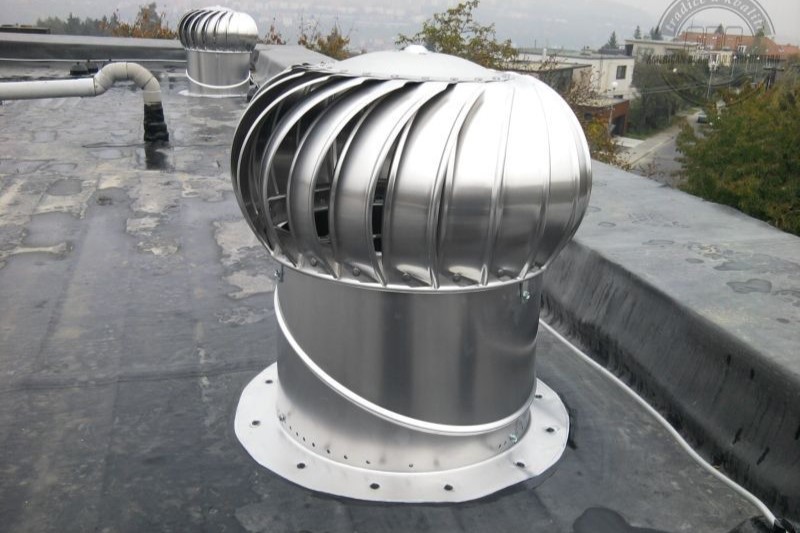 Lomanco is a reputable whirlybird roof vent brand. Image shows a shiny, silver whirlybird installed on a roof, on a rainy day.