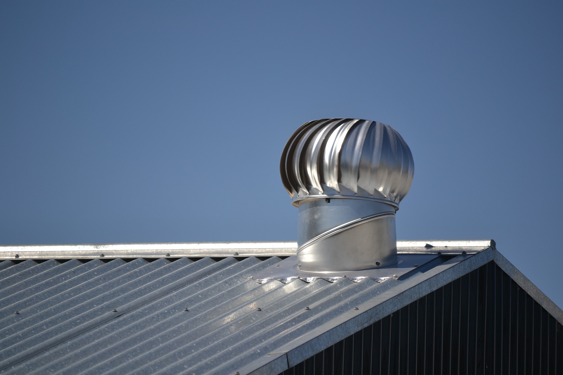 A shiny, silver whirlybird roof vent installed on a roof on a sunny day
